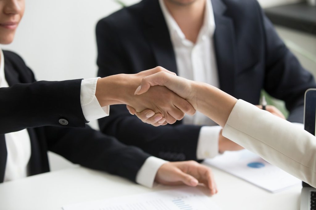 Business professionals shaking hands over contract documents representing PPA agreements