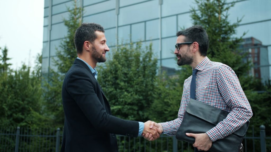 Business partners meeting outdoors shaking hands showing collaboration and partnership